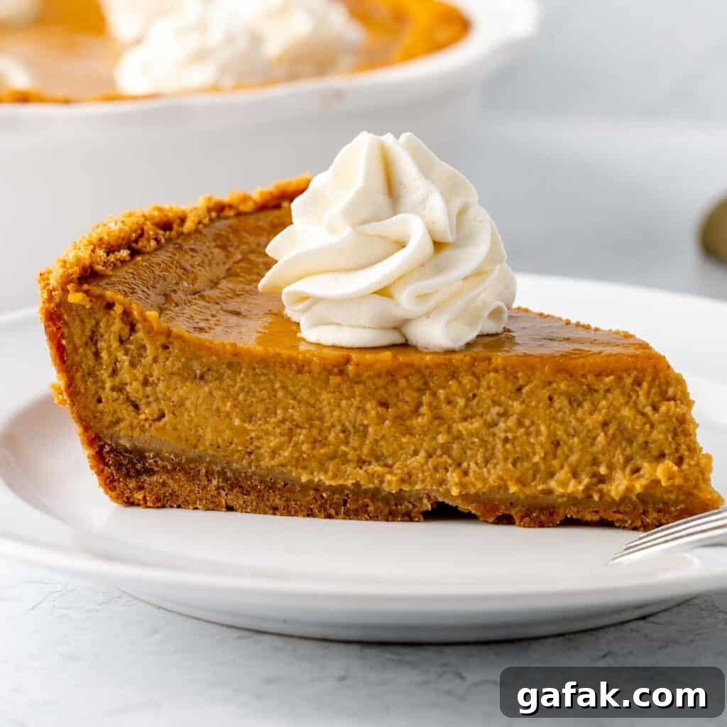 Mini Pumpkin Hand Pies: Flaky Autumn Pastry Recipe 22 A slice of pumpkin pie on a white plate, topped with whipped cream.