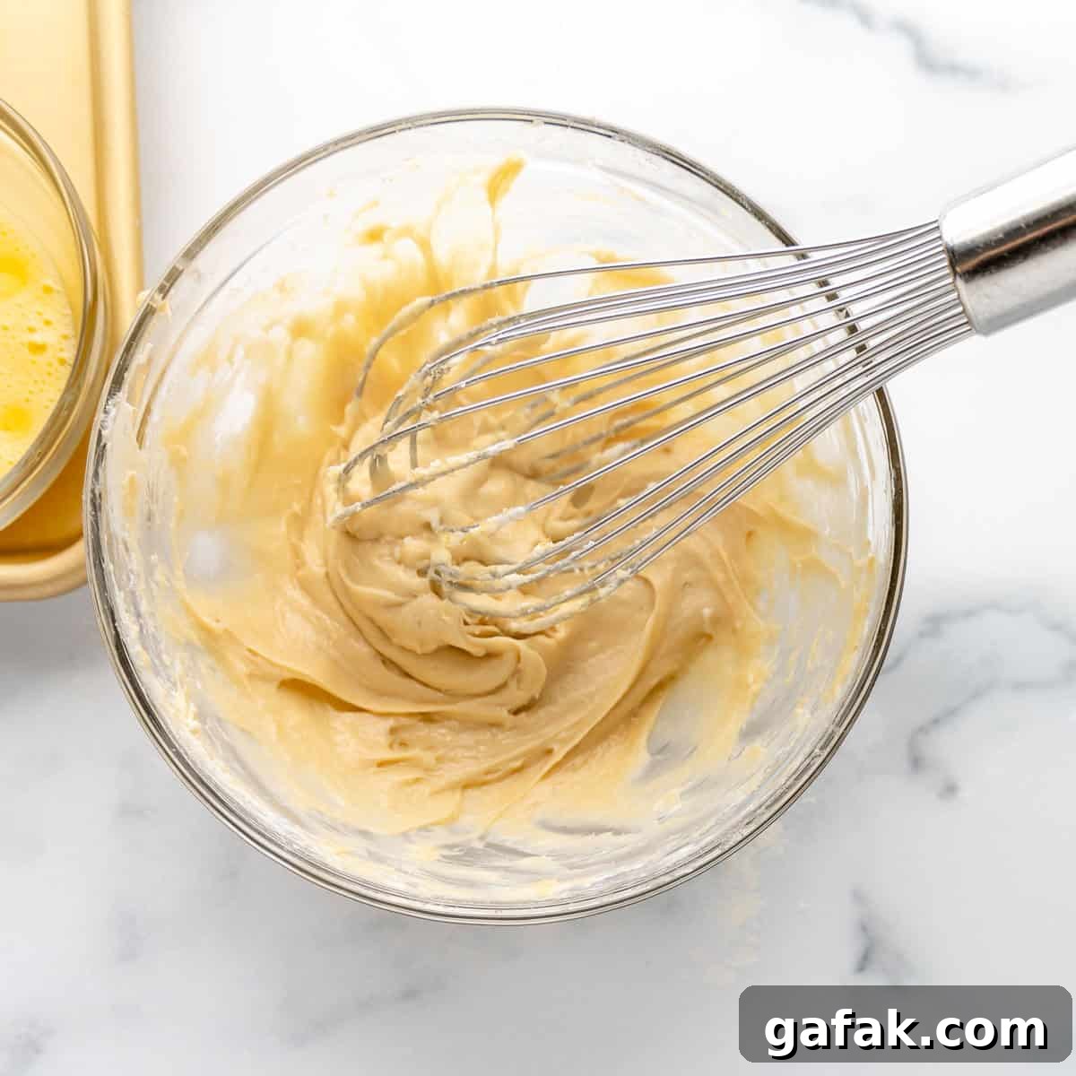 Mini Pumpkin Hand Pies: Flaky Autumn Pastry Recipe 6 A whisk mixing together ingredients in a clear bowl.
