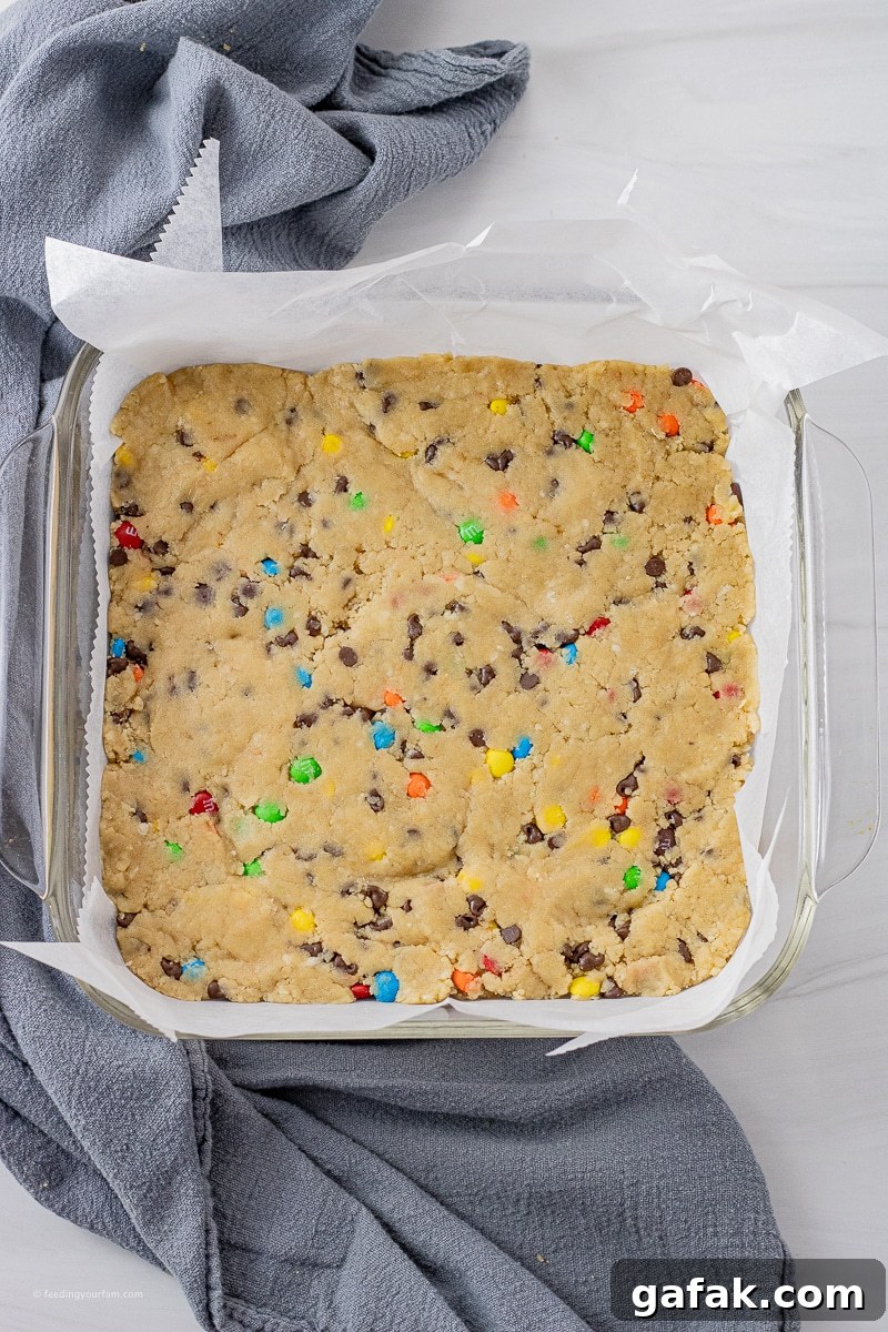 No-Bake Chocolate Chip Cookie Dough Bars Recipe for Dessert 3 uncooked chocolate chip cookie dough bars with mini chocolate candy pieces pressed into a square baking pan