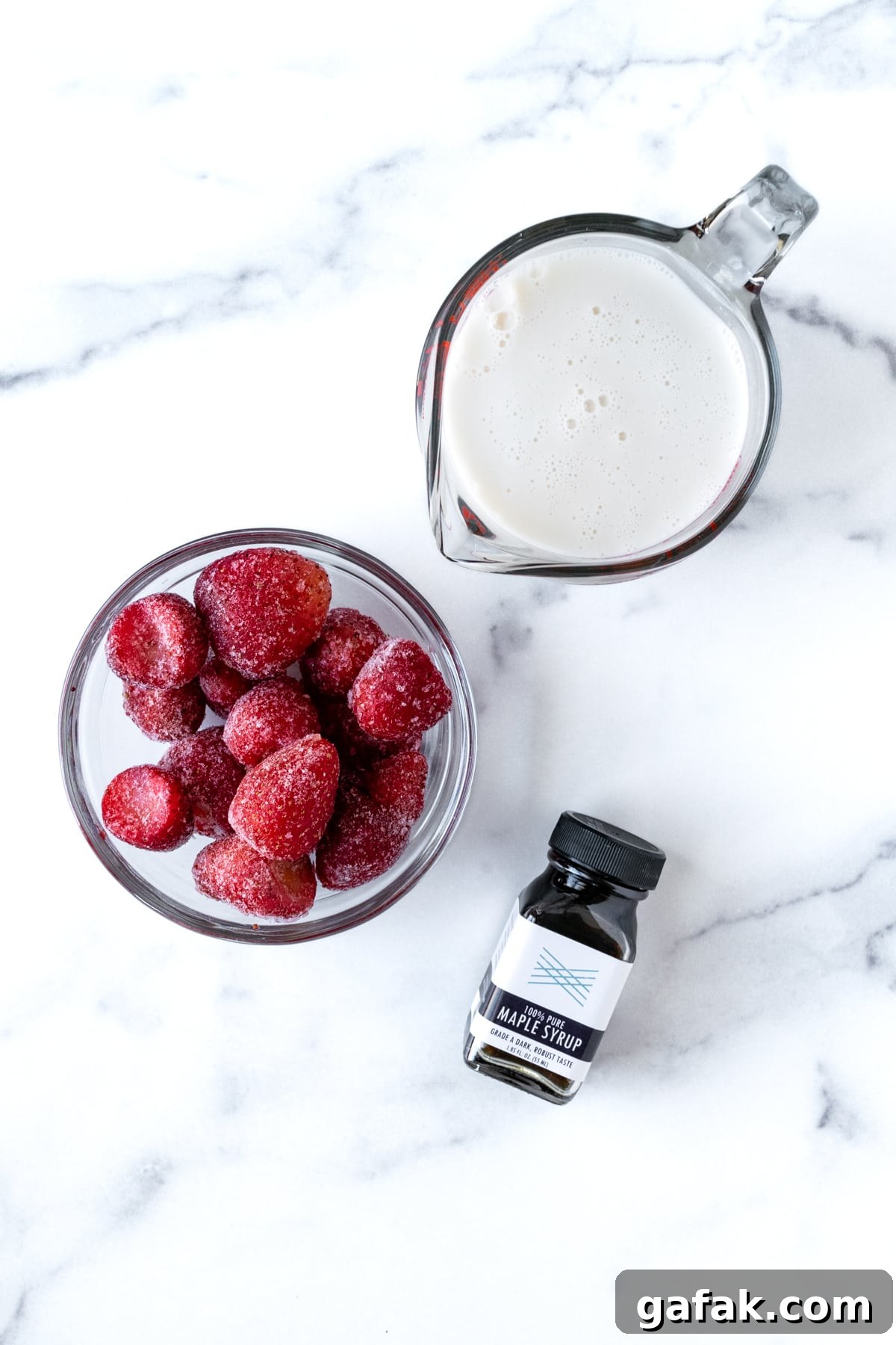 Almond Milk Strawberry Smoothie Ingredients on a marble countertop.