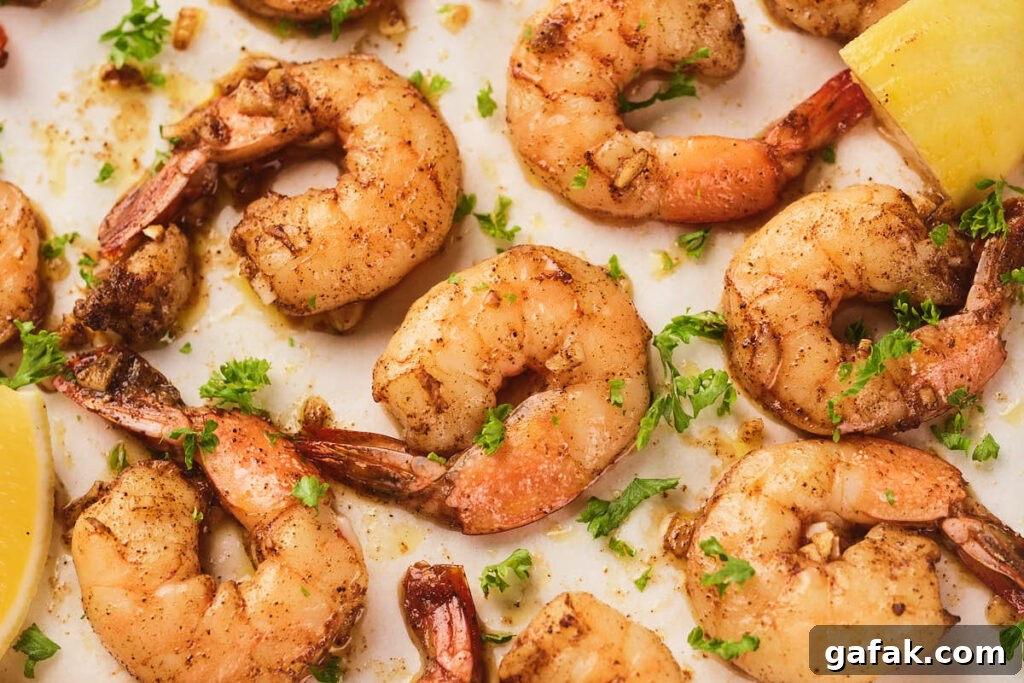 Cooked garlic butter shrimp seasoned with spices and garnished with chopped parsley.