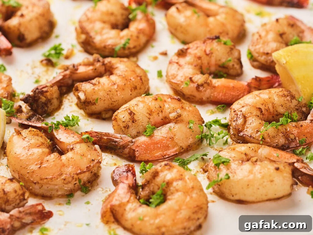 Garlic butter shrimp garnished with chopped parsley with a lemon wedge visible in the corner.