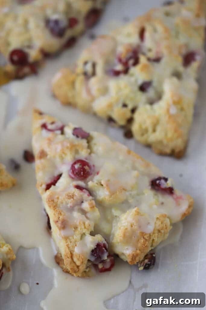 Cranberry orange cream scones cut into triangles and topped with orange glaze.