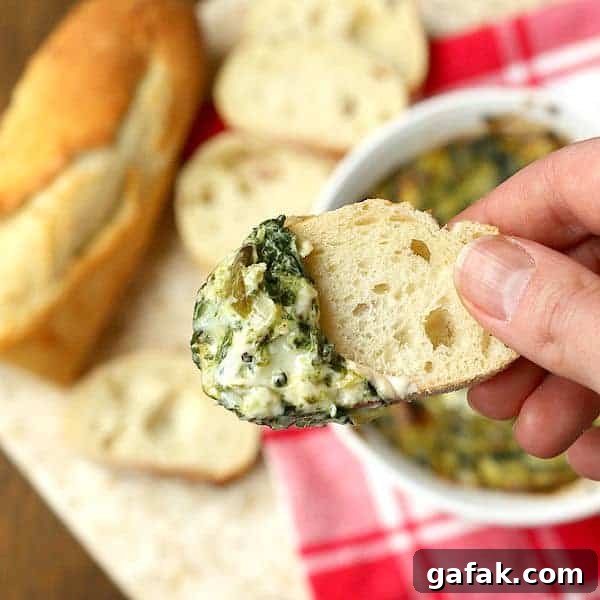 Overhead photo of spinach artichoke dip on a slice of baguette