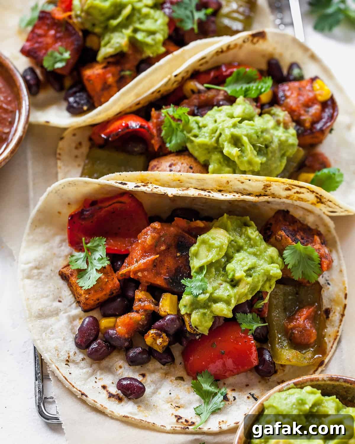 overhead view of three black bean sweet potato tacos with guacamole