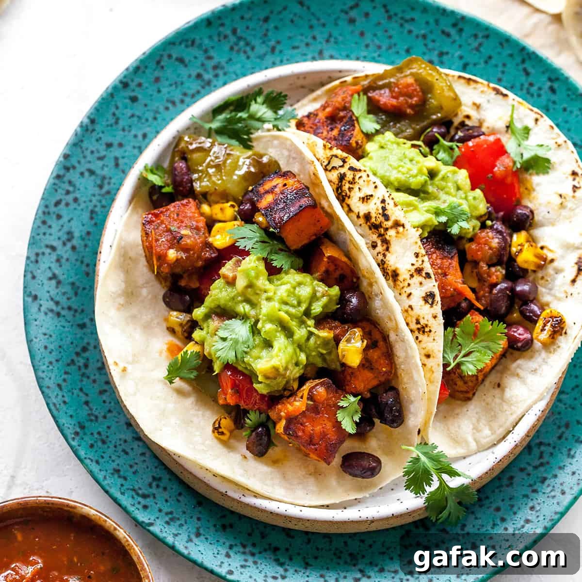 overhead view of three black bean sweet potato tacos with guacamole on a plate