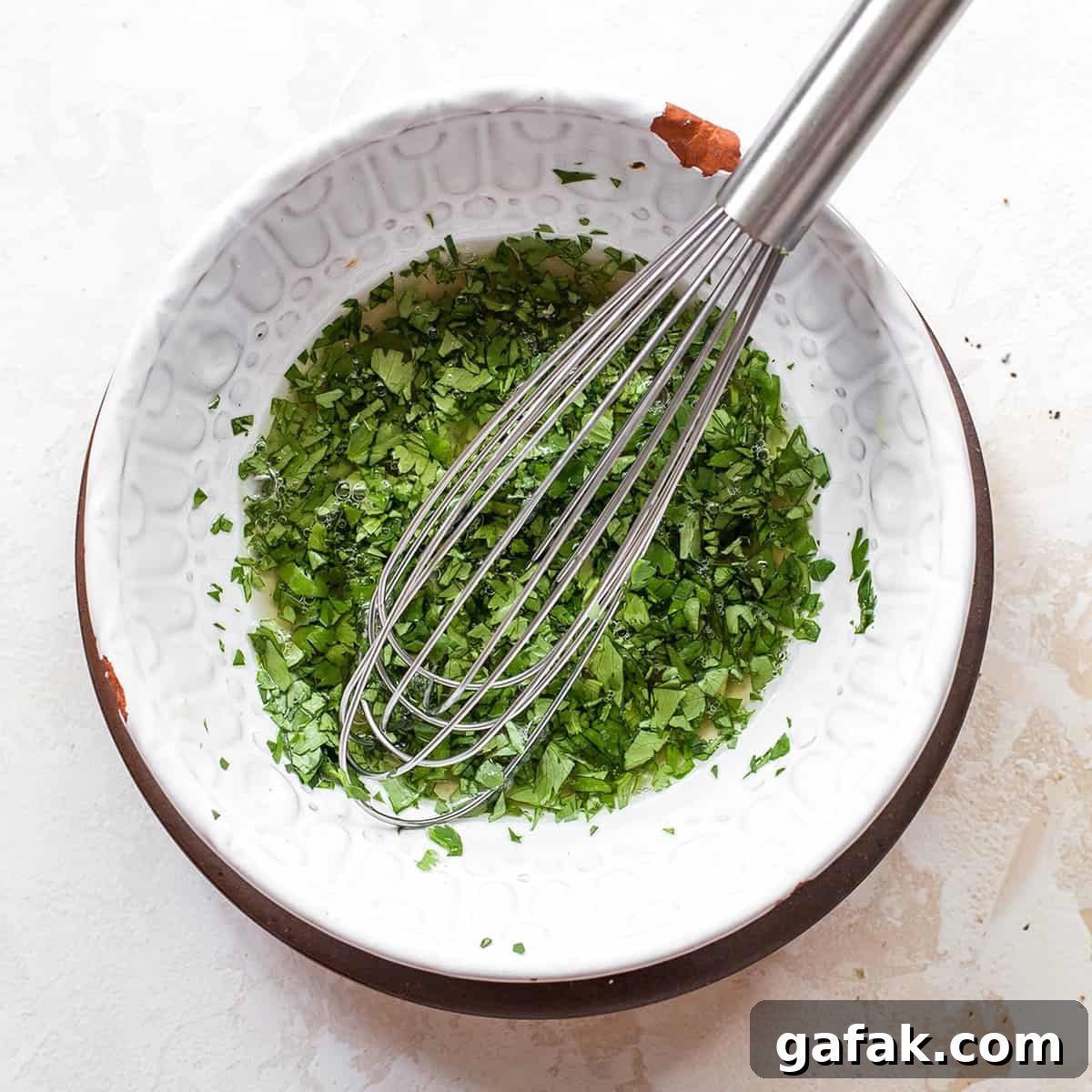 whisking together the sauce for sweet potato tacos in a white bowl