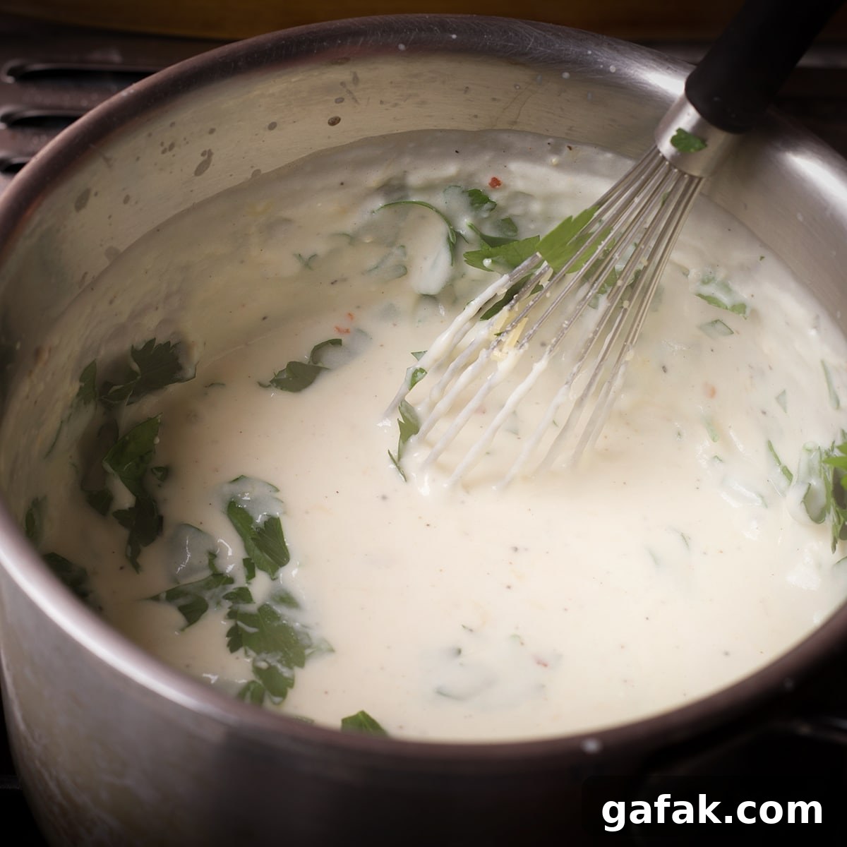 Creamy Mushroom Lasagna with Parmesan Béchamel Sauce 10 Adding chopped Italian parsley to béchamel sauce as it cooks in a saucepan.