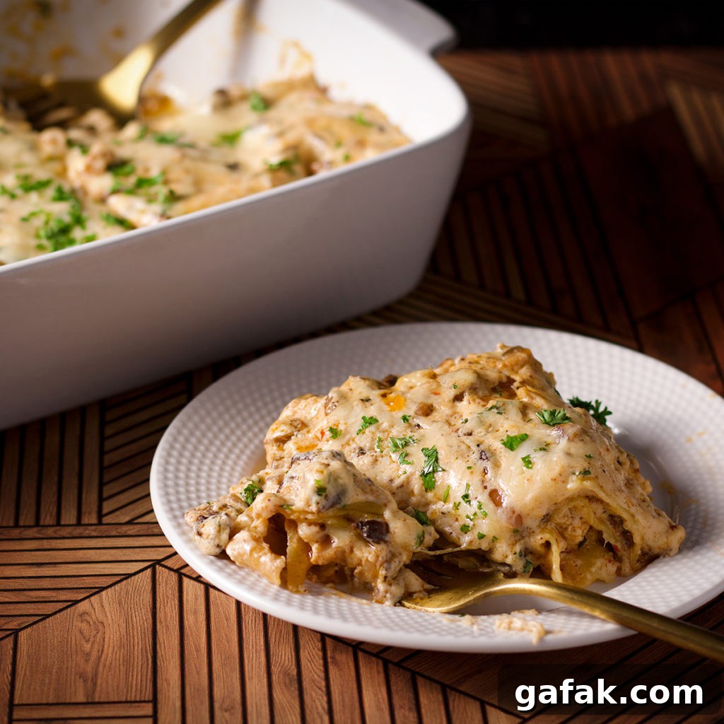 Creamy Mushroom Lasagna with Parmesan Béchamel Sauce 16 A piece of white mushroom lasagna on a plate with a fork.