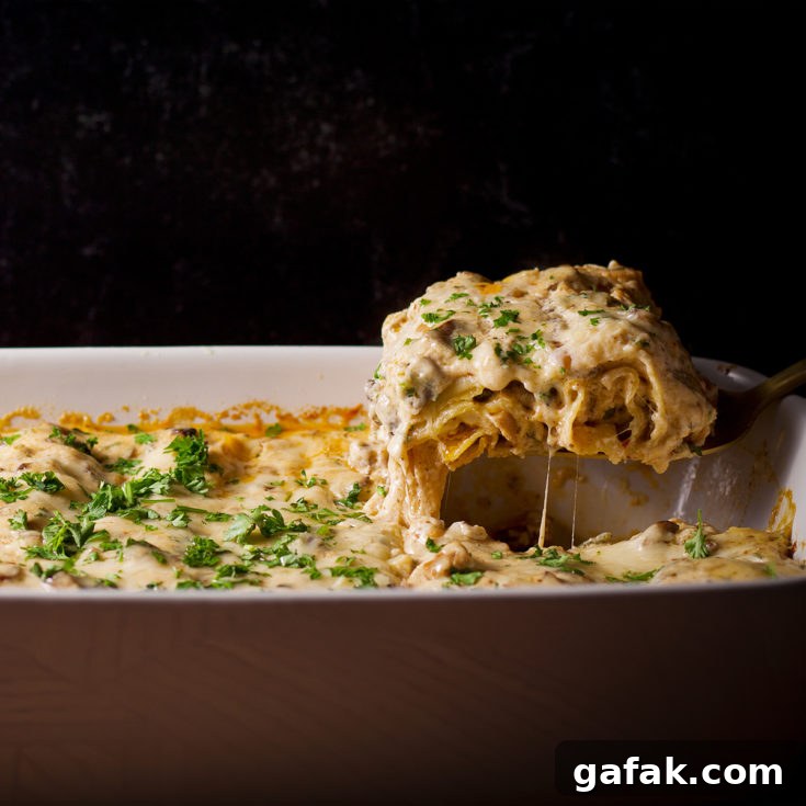 Someone using a spatula to serve a piece of white mushroom lasagna.