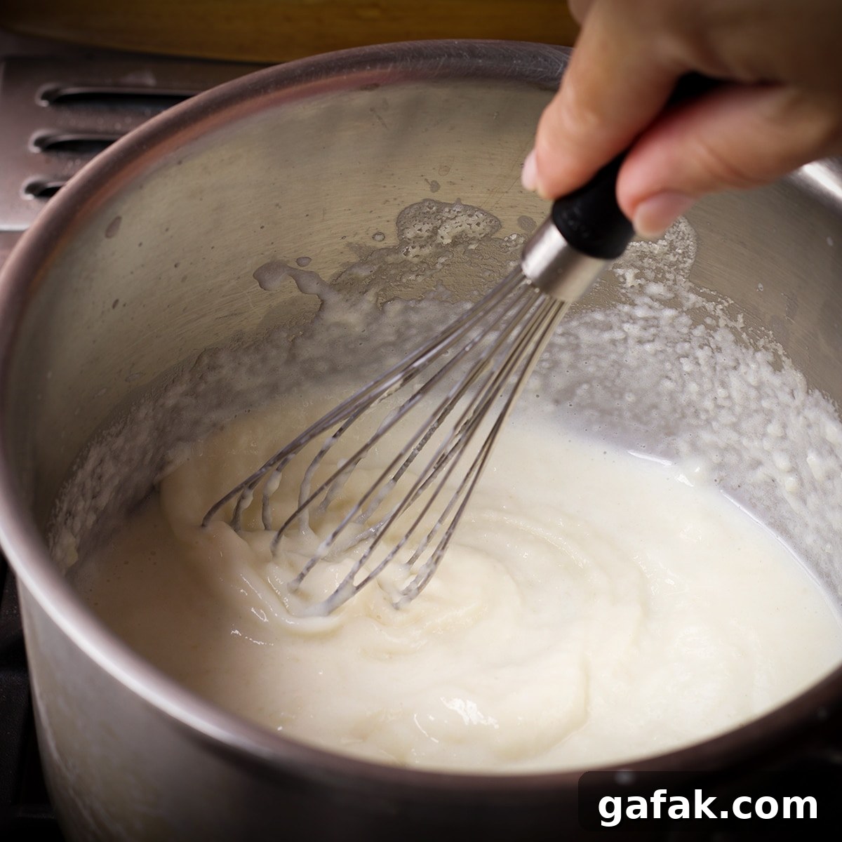 Creamy Mushroom Lasagna with Parmesan Béchamel Sauce 6 Slowly adding milk to roux in a saucepan to make Béchamel sauce.