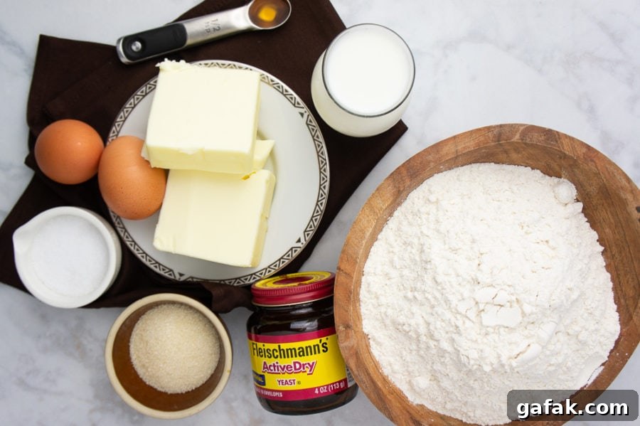 a big bowl of flour with butter, cream cheese, eggs, milk, and yeast beside it