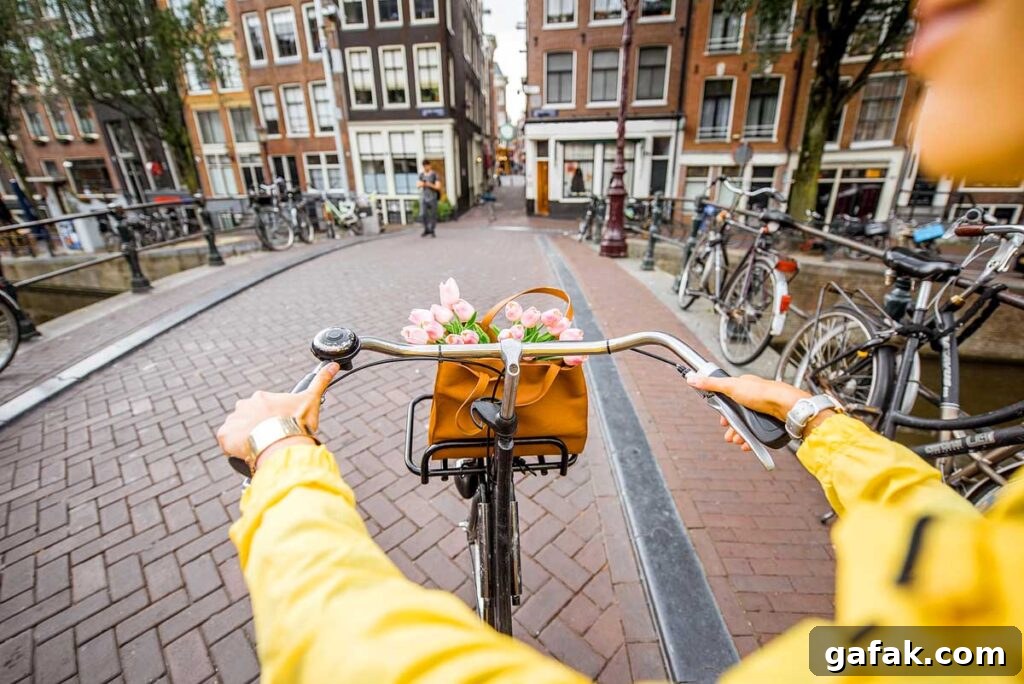 Woman riding a bicycle with bouquet of flowers on the street in Amsterdam city.