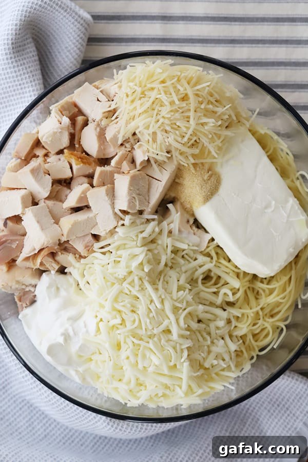 Ingredients to make this Chicken Spaghetti casserole recipe in a glass mixing bowl.