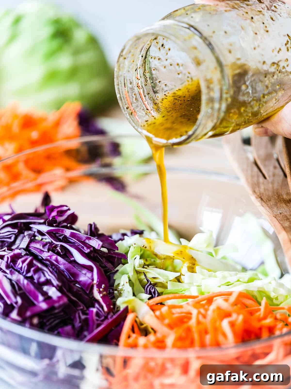 Vinegar coleslaw dressing in a jar beside a bowl of slaw.