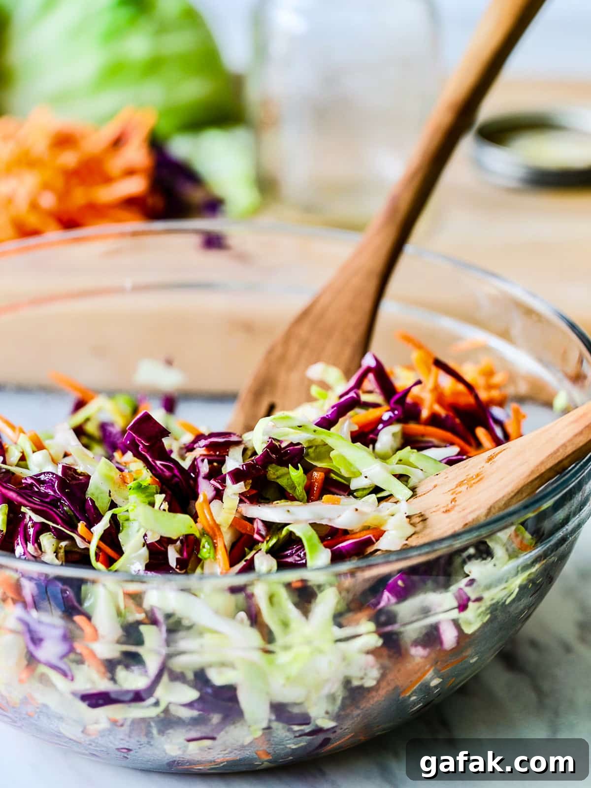 Tossing coleslaw in a bowl with wooden tongs.