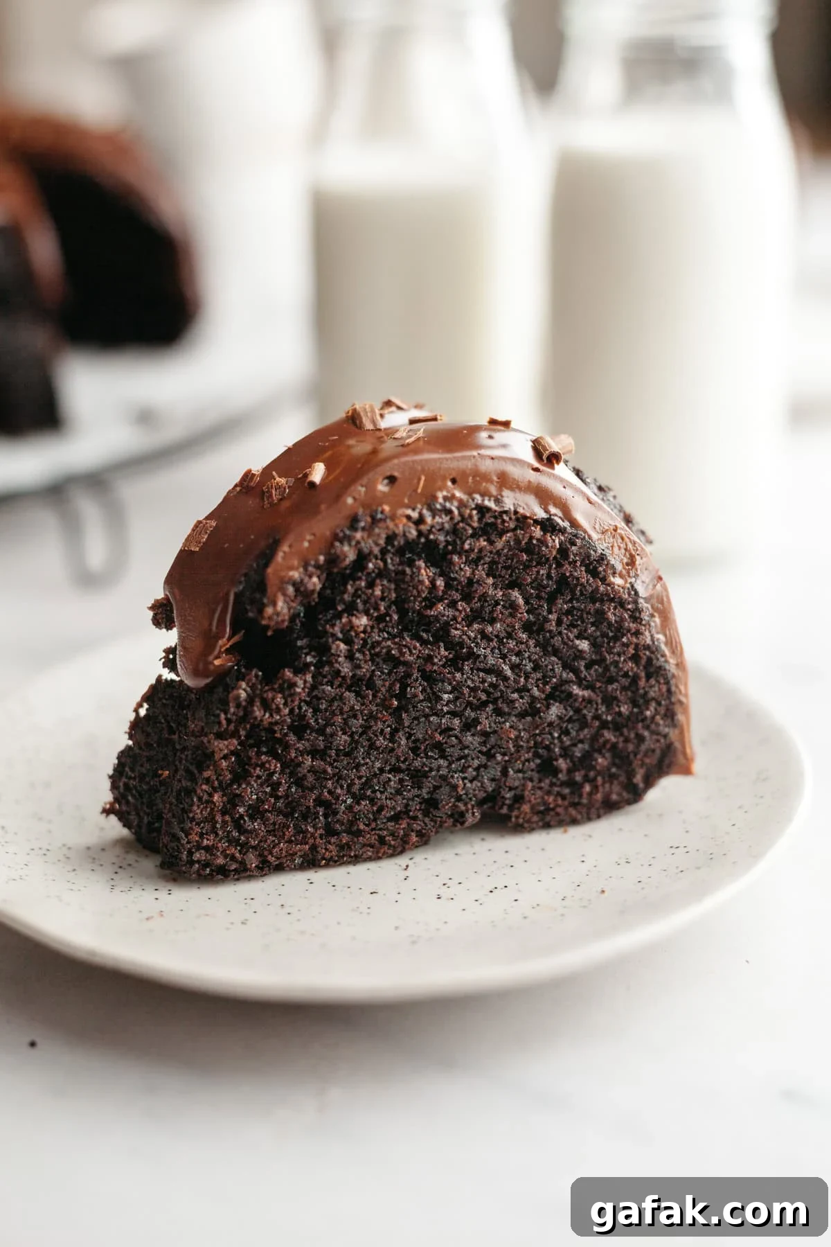 A slice of double chocolate bundt cake with ganache on a small plate.