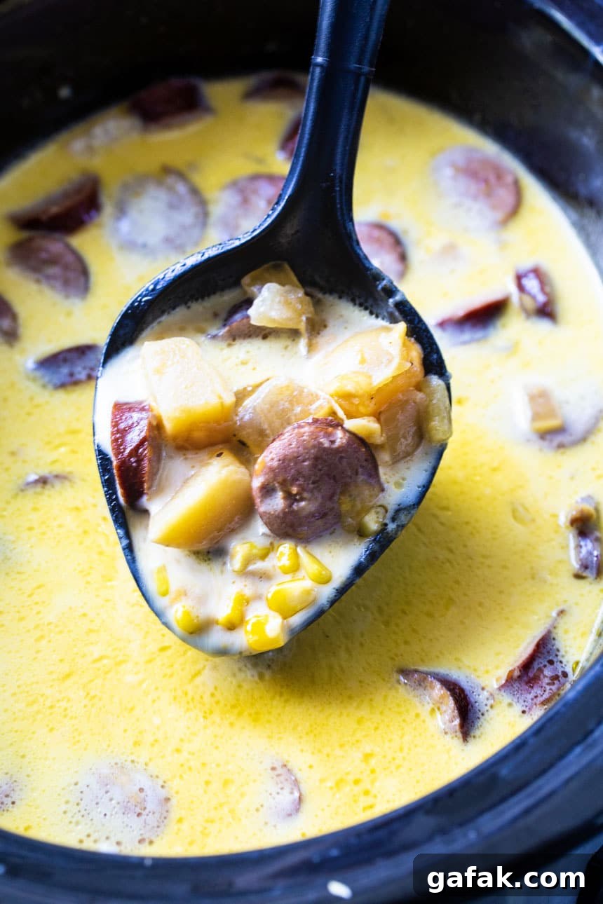 Spoon scooping chowder out of slow cooker.
