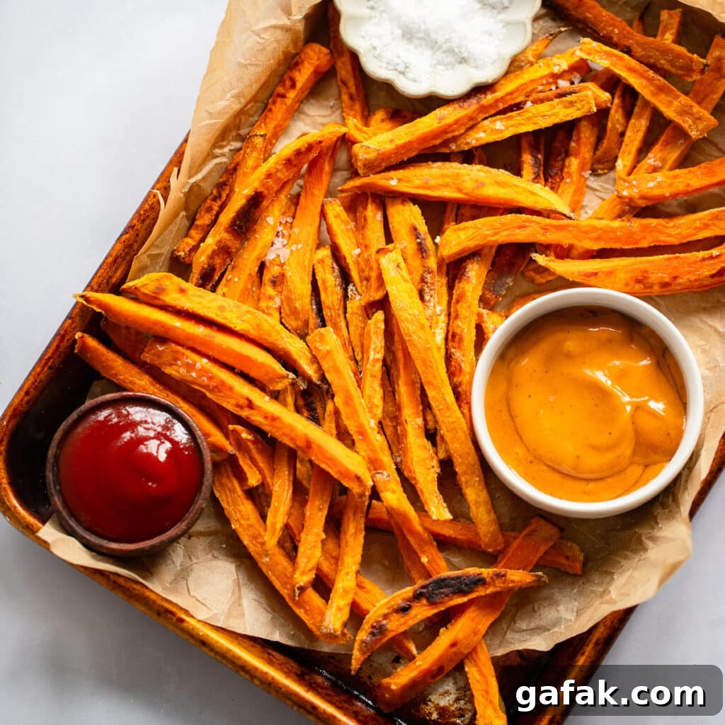 baked sweet potato fries on baking sheet with topping sauces in bowls