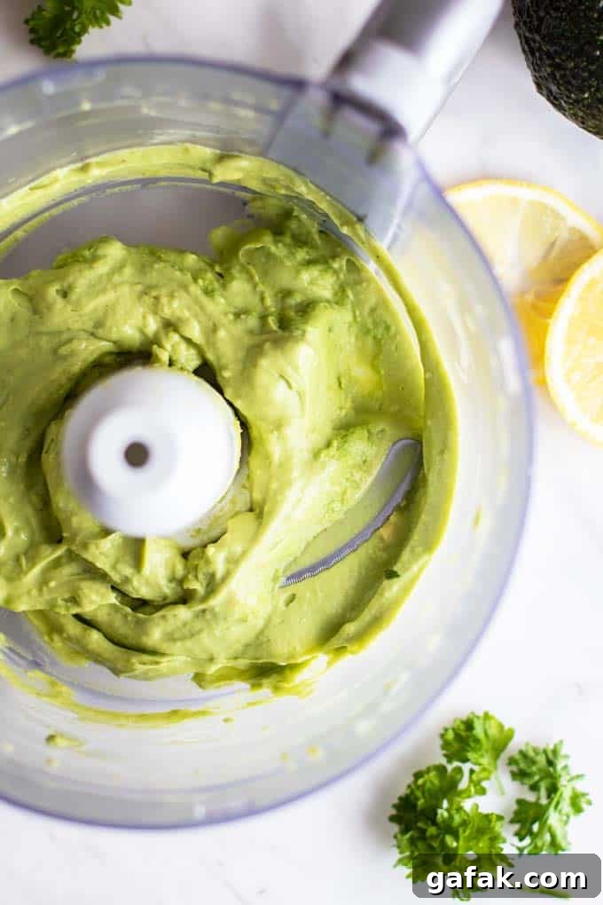 A food processor showing the consistency of creamy avocado sauce.