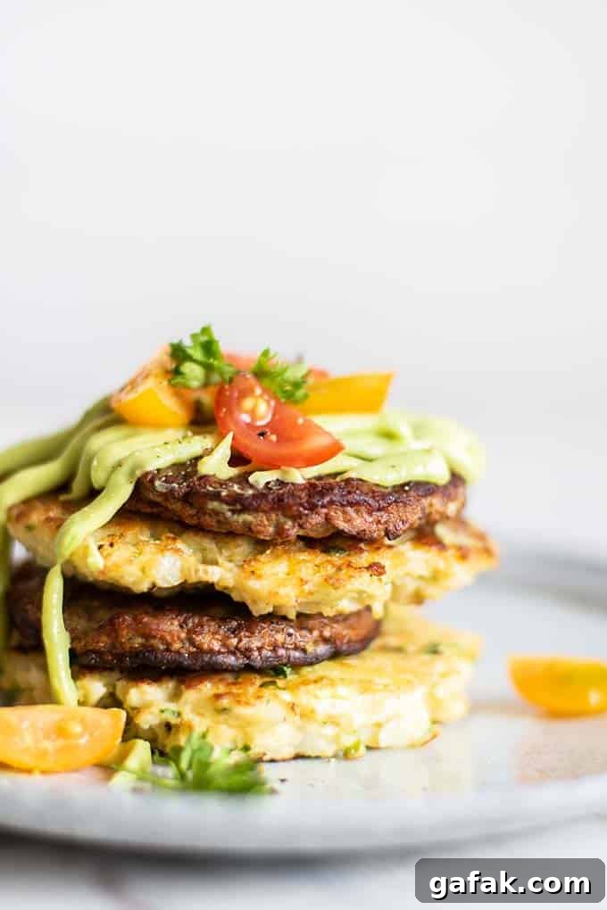 A close up view of perfectly browned cauliflower fritters and sausage, drizzled with avocado sauce.
